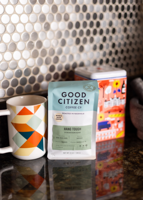 Hang Tough coffee bag on counter with mug and tea box