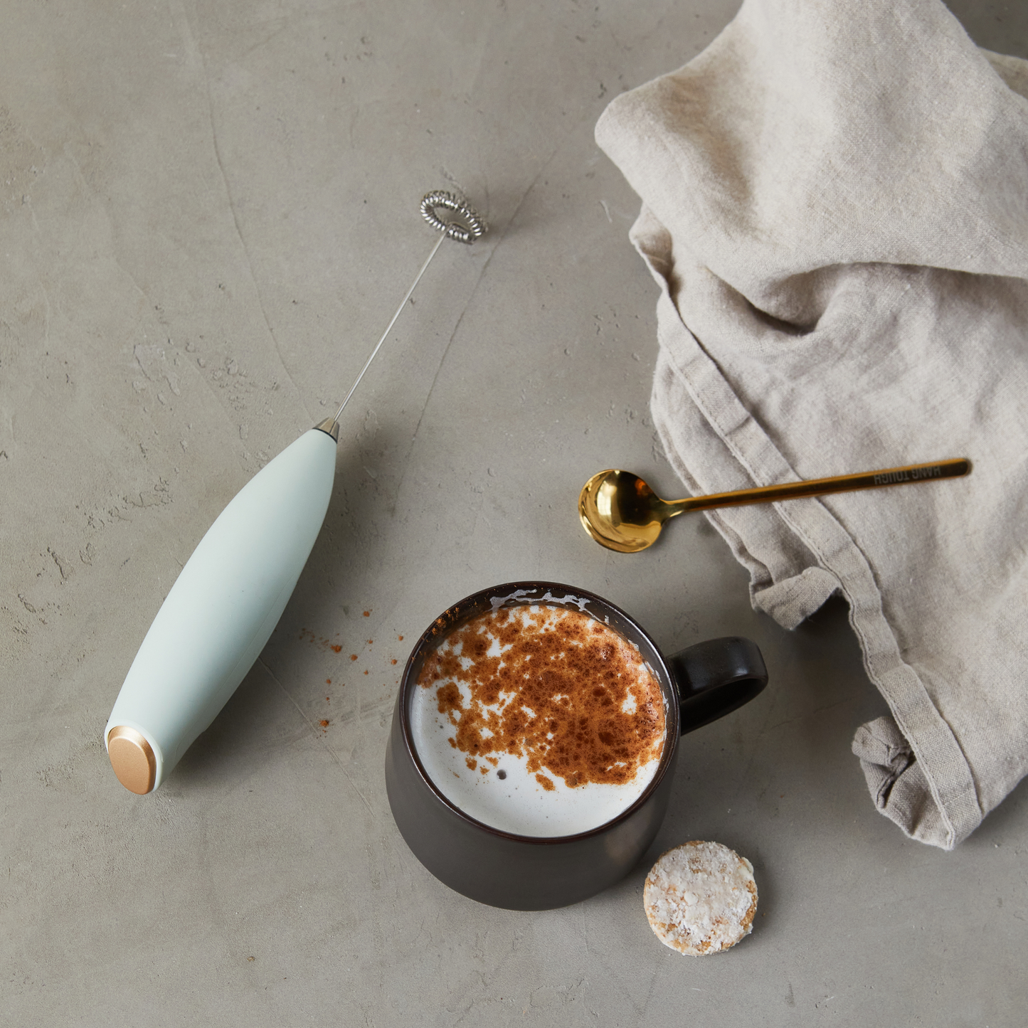 frother and spoon next to cup of coffee