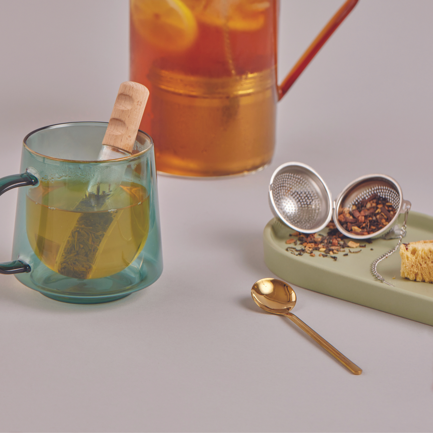 mug next to a spoon and tea in an infuser