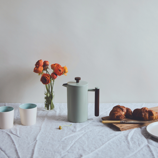 Sage Green French press on table with orange florals in background