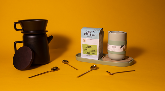 Masha Coffee bag on a tray with a tumbler mug and a pourover pot on orange-yellow background