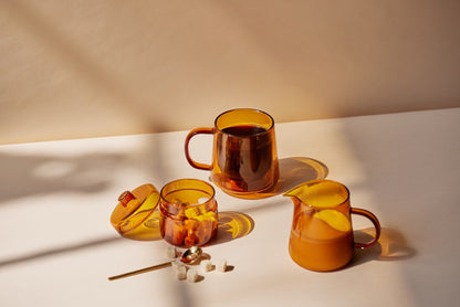 glass pitcher and jar and mug filled with coffee with sugar cubes