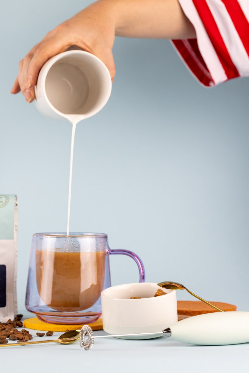 mug with coffee and cream being poured inside