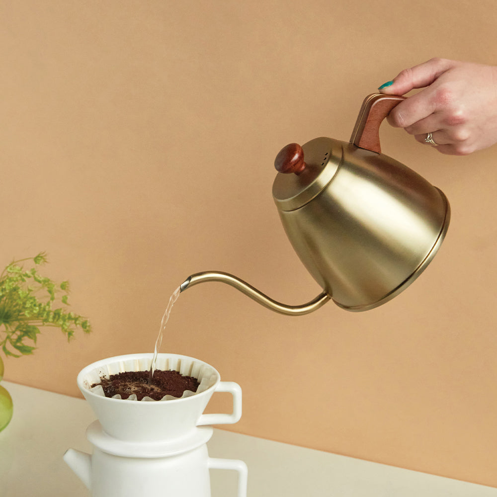 gooseneck kettle in use pouring water into the white ceramic pour over coffee maker